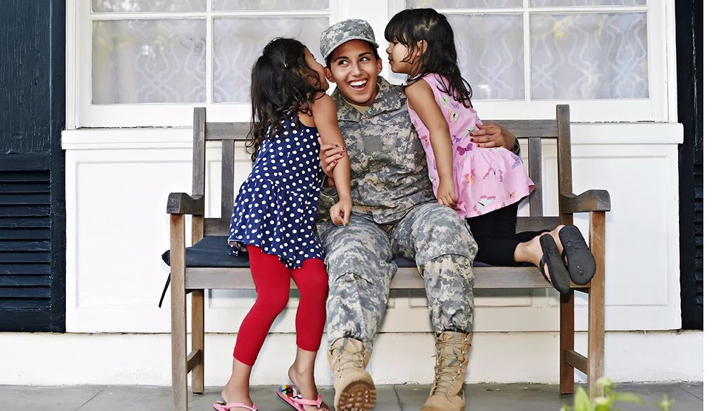 Thanking a soldier can help you both feel more positive A female soldier with two young girls on a patio