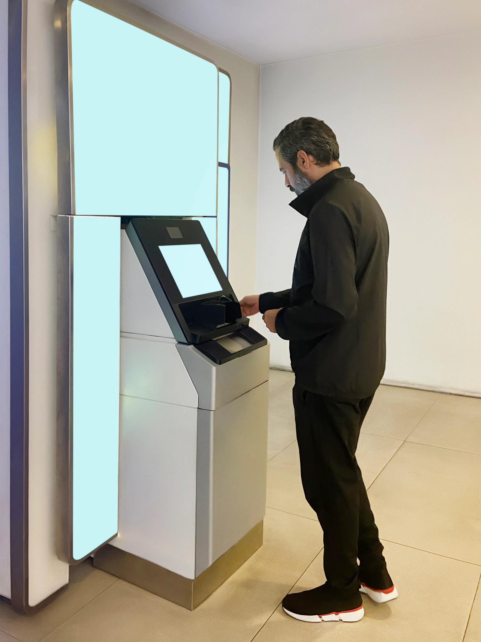 Young adult man using ATM banking machine with blank screens