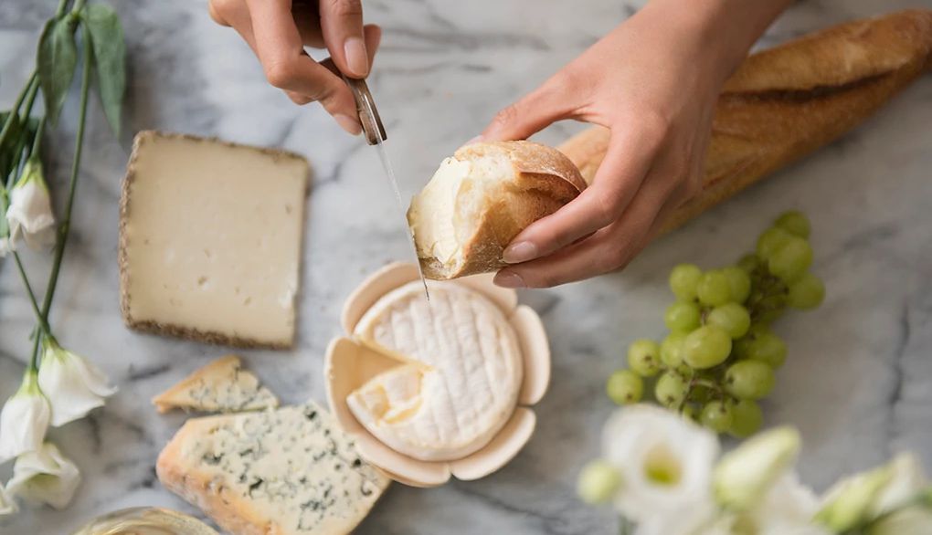 Dairy can help provide a protein and calcium boost Hands of a person using a knife to spread cheese on bread