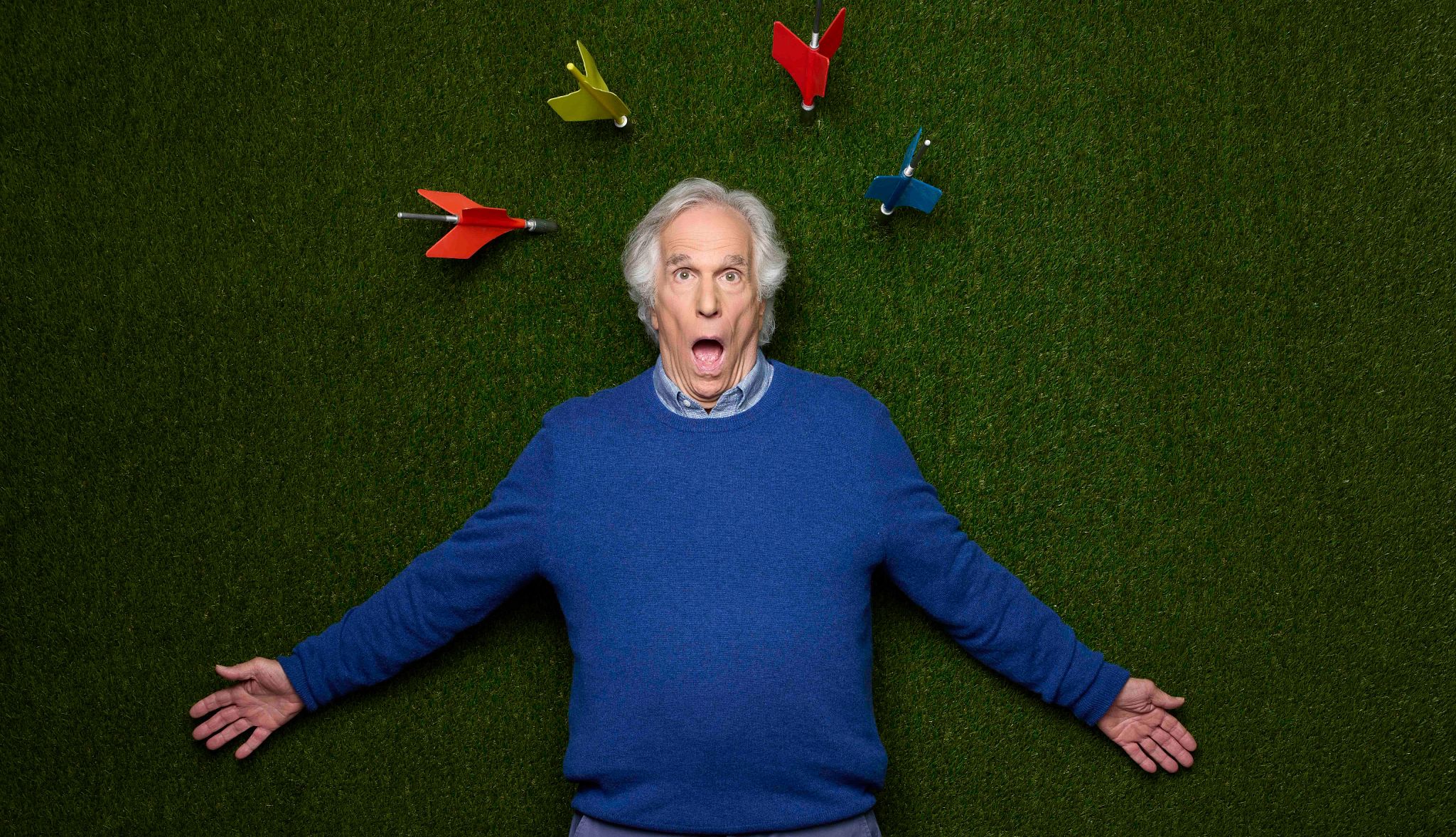 Henry Winkler: ‘My Whole Life Is a Bet’  Henry Winkler making a comical surprised face while lying on an astroturf background with his head surrounded by lawn darts