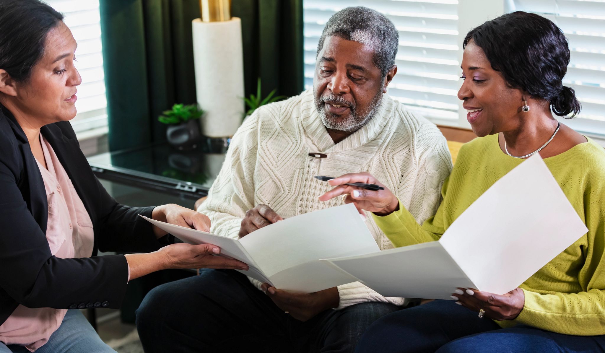 A senior African-American couple meeting with an in-home consultant in their living room signing paperwork A senior African-American couple meeting with an in-home consultant in their living room signing paperwork