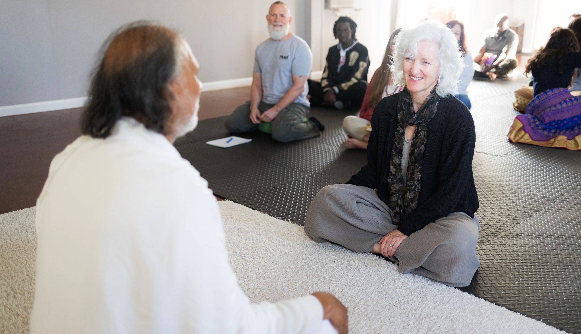Participantes sentados sobre colchonetas de yoga durante una clase en el Siddhayatan Tirth & Spiritual Retreat, en Texas