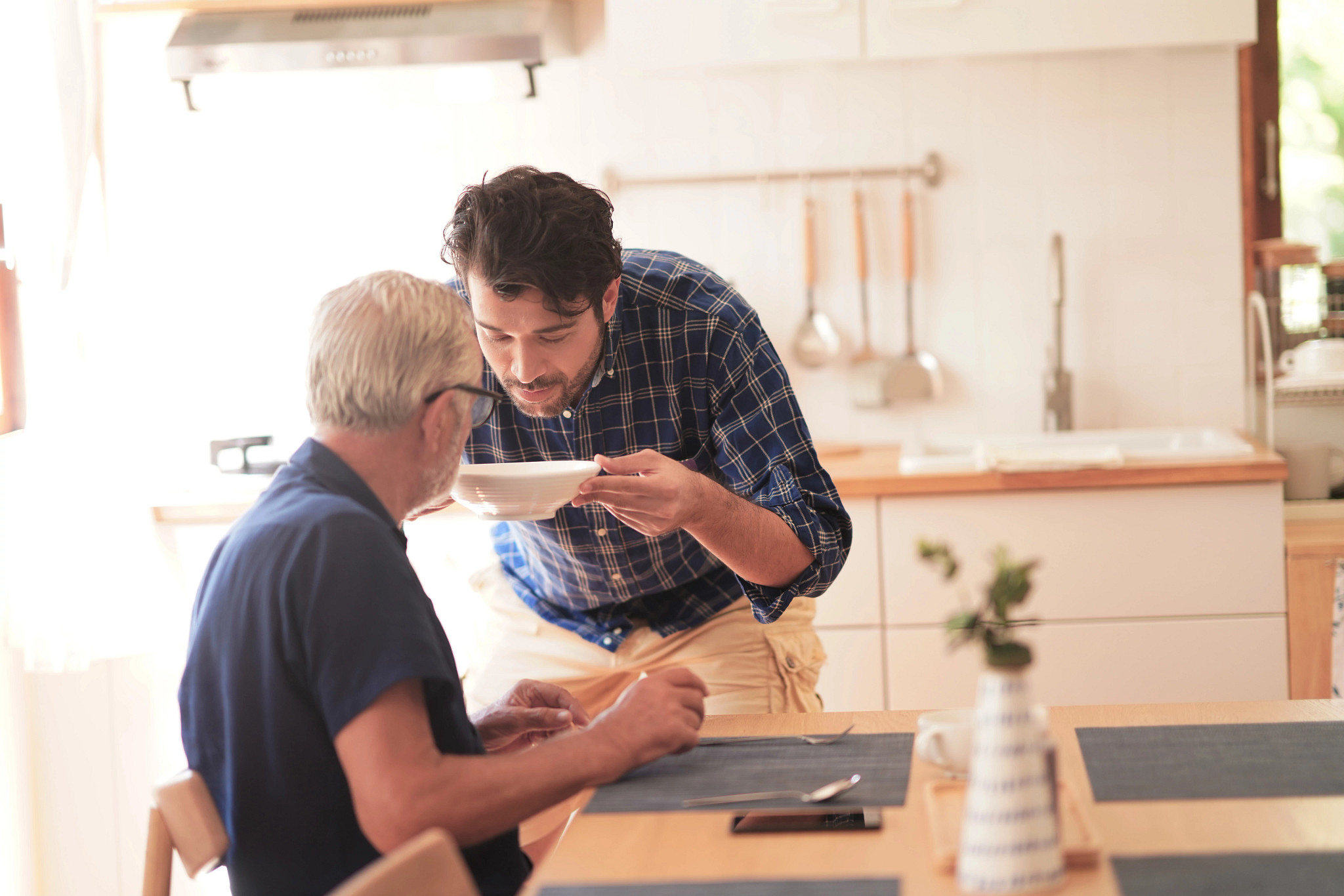 Young adult son and Elderly father sitting in the kitchen room take a breakfast, Son caring his father family relationship domestic life