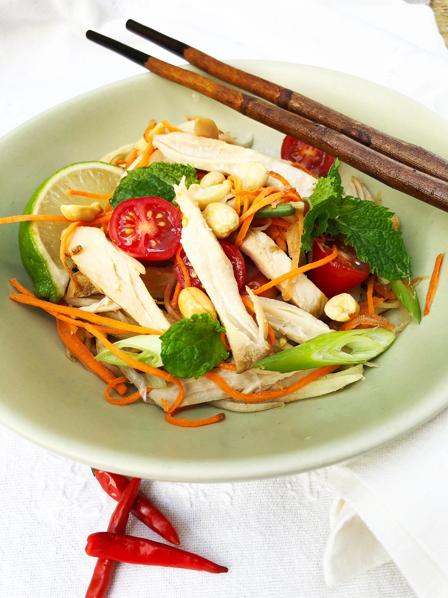 Salad consisting of  lettuce, cut up chicken breast, shredded mangoes, tomatoes and carrots in bowl