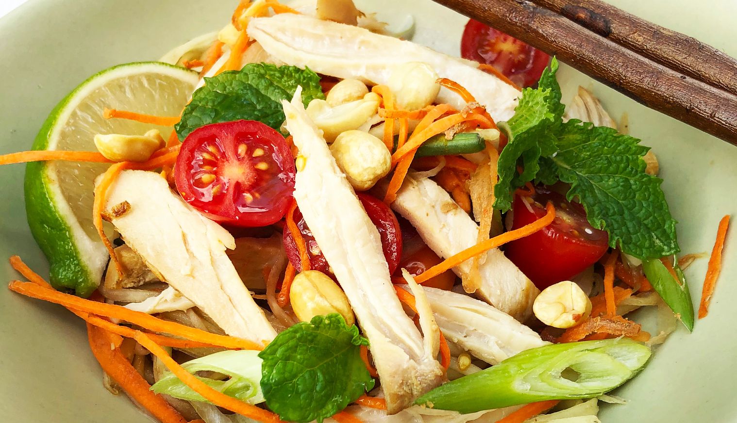 Chef Dennis Chan's Asian Chicken and Green Mango Salad Salad consisting of  lettuce, cut up chicken breast, shredded mangoes, tomatoes and carrots in bowl
