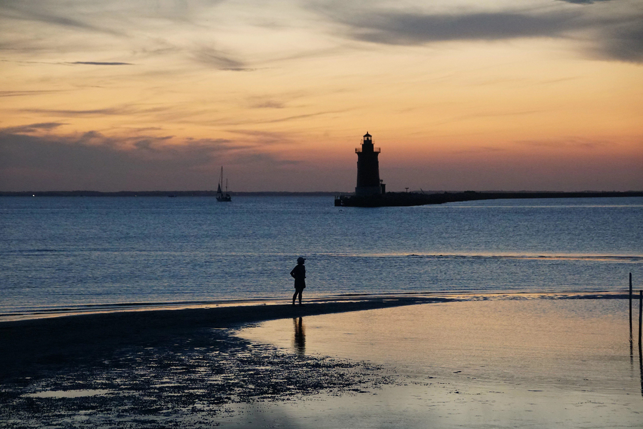 Silueta del faro y una chica durante el atardecer cerca del Parque Estatal Cape Henlopen