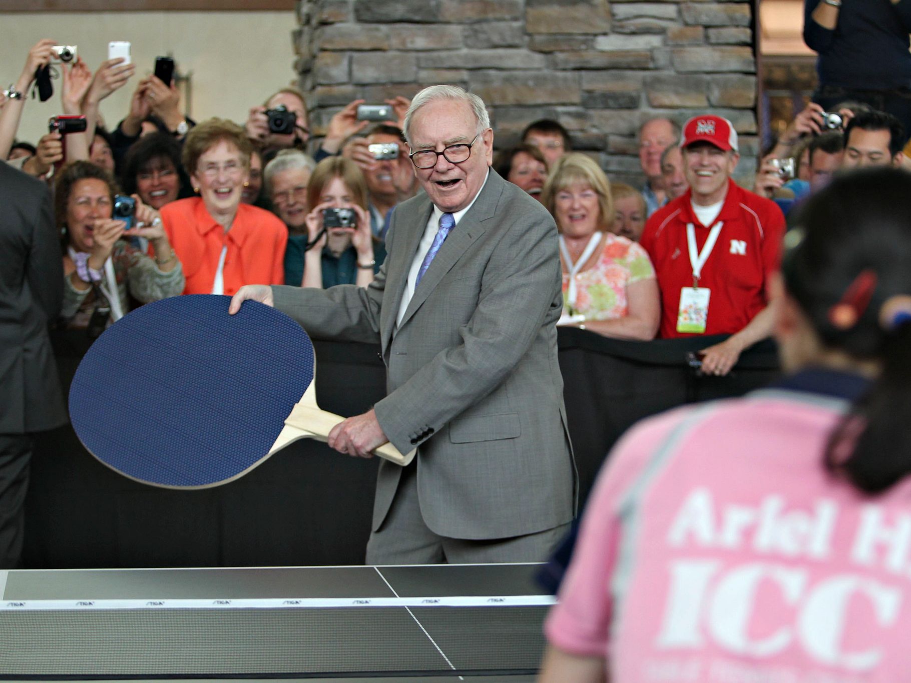 Warren Buffet holding a comically oversized table tennis paddle