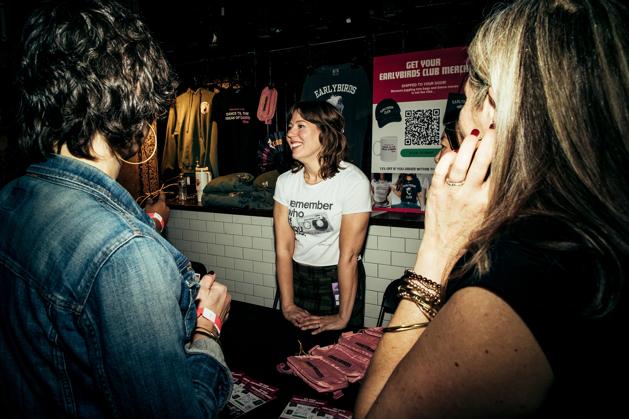 a photo shows Laura Baginski working the merch table at an Earlybirds Club dance party