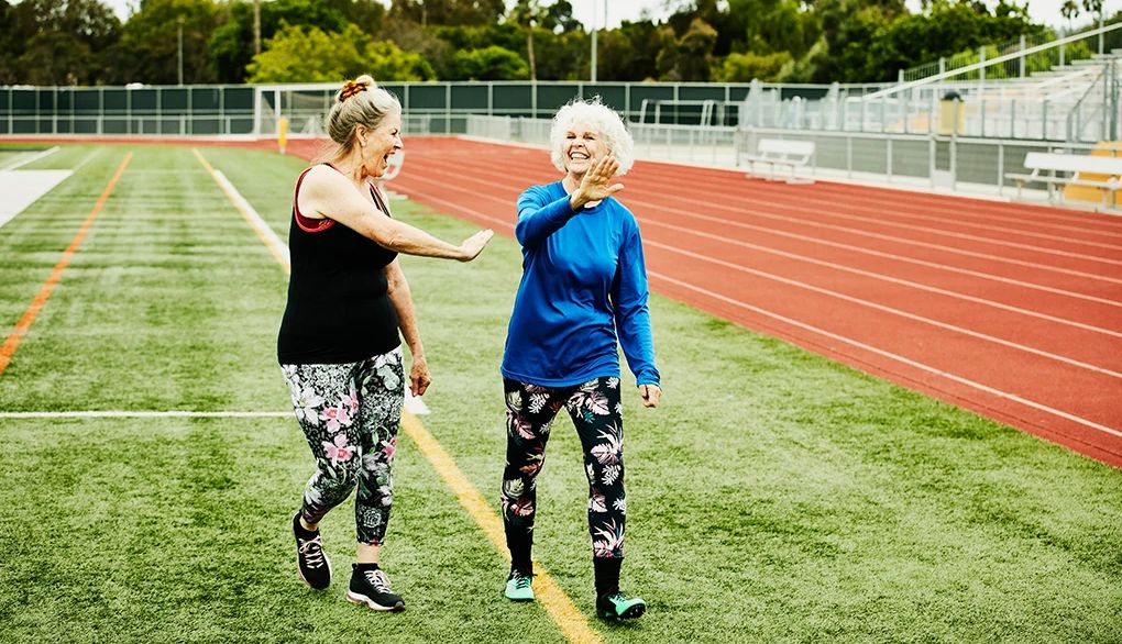 Friendship and fitness are a great combination Two women smiling and walking together beside a track
