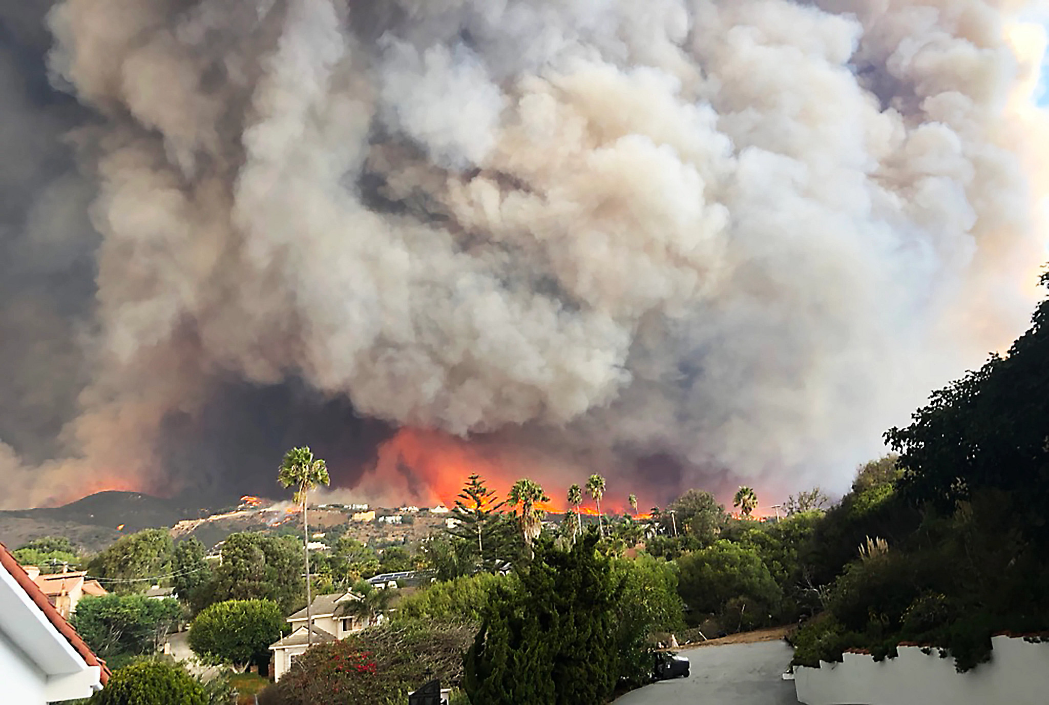 Wildfire burning on a hillside with heavy smoke overhead