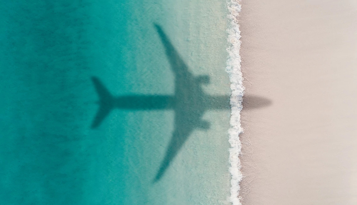 Flights & Vacation Packages Category Silhouette of airplane shadow over a tropical beach