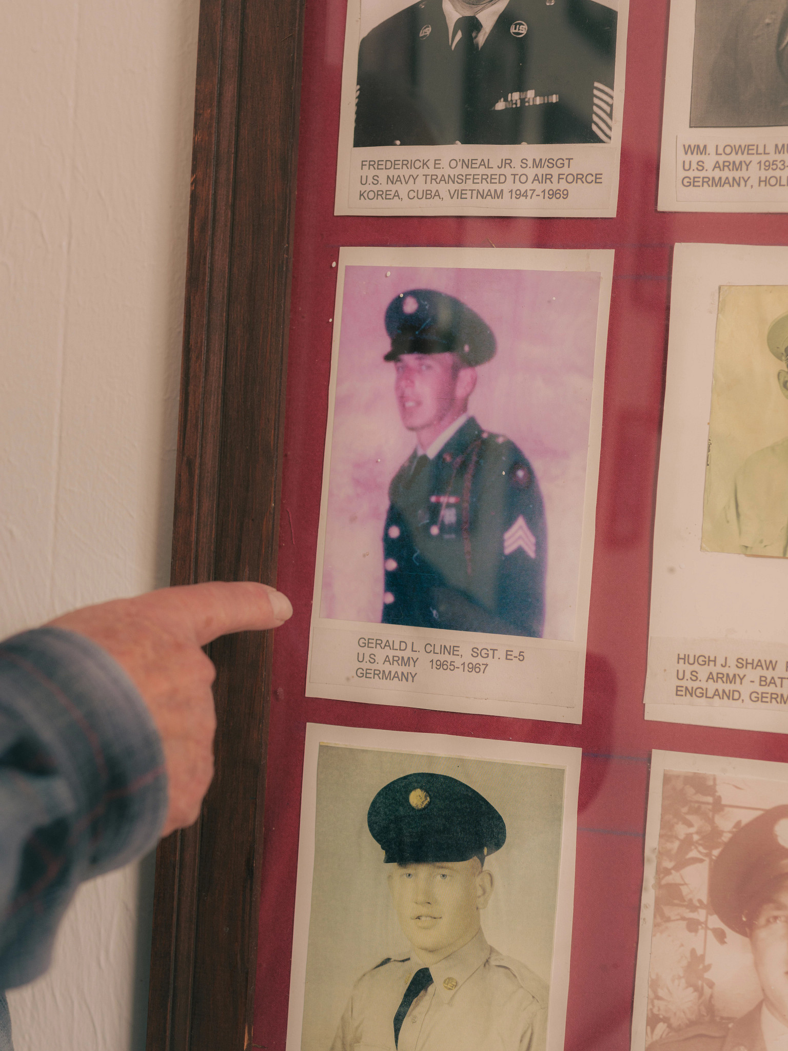 Gerald Cline pointing to a framed picture of himself as an Army soldier