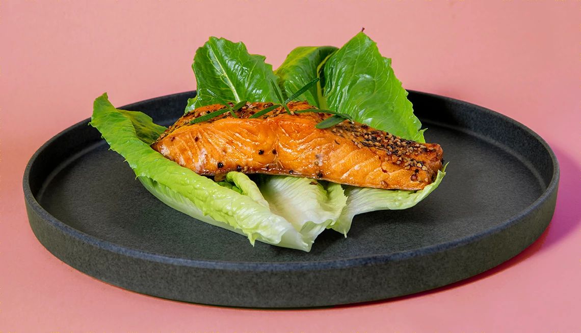 Smoked Salmon slice on black plate with yellow background Smoked Salmon slice on black plate with yellow background