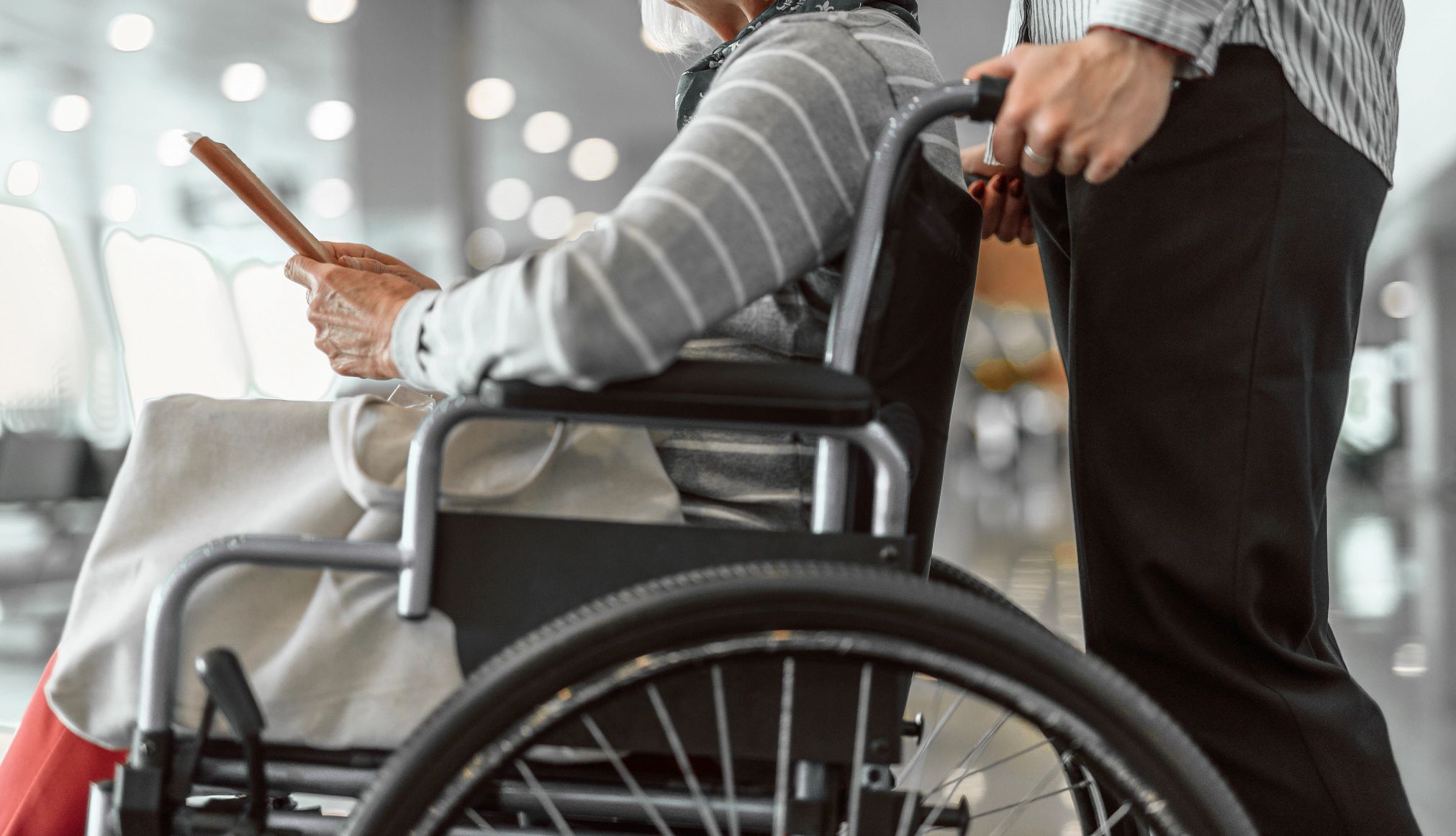 Tips for Traveling With Older Parents a caregiver pushes an adult in a wheelchair