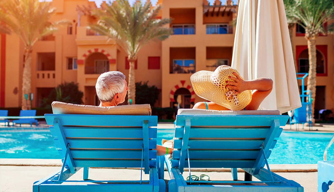 Couple sitting poolside at tropical resort with palm trees