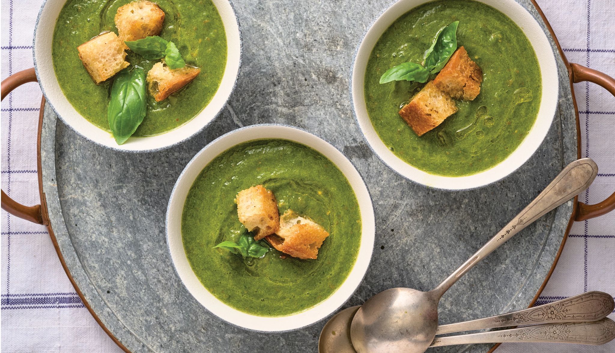 Green Gazpacho Recipe three bowls of green gazpacho on a tray next to three spoons