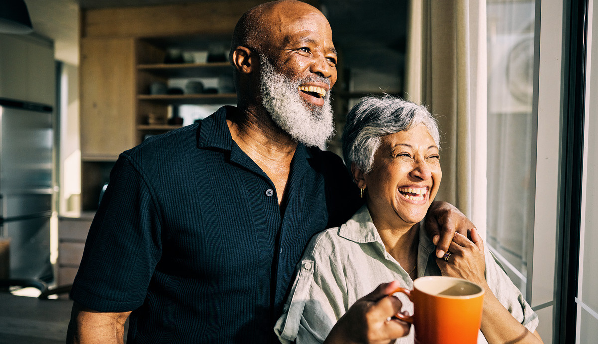 Image of an older happy couple, looking out the window laughing