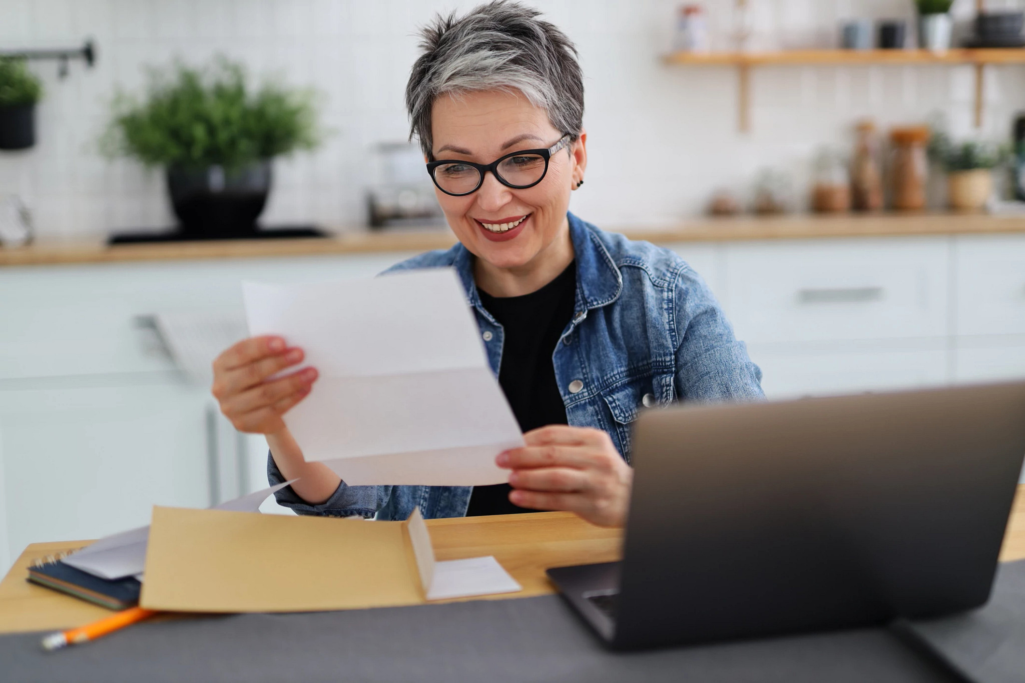 A senior African-American couple in their 60s sitting at home at their dining room table, looking at documents and talking with a financial advisor. The advisor is a mature African-American woman in her 50s.