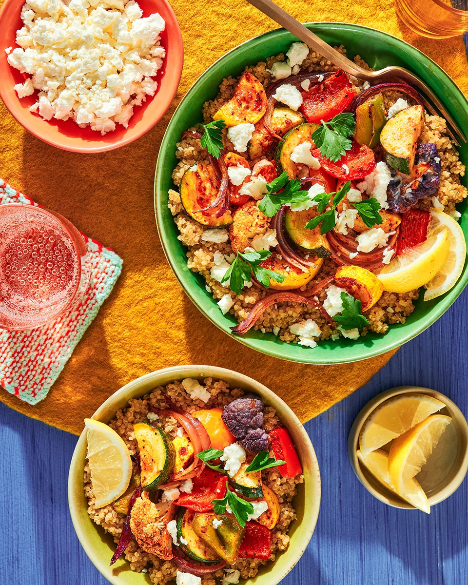 Vegetarian grain bowls topped with roasted vegetables, feta cheese, and fresh herbs