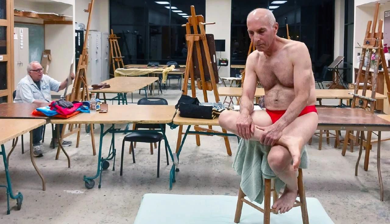 I’m a Nude Model at 73 a photo shows Harold Kahn, wearing a speedo, atop a stool posing for a life drawing class at his Florida retirement community’s arts club
