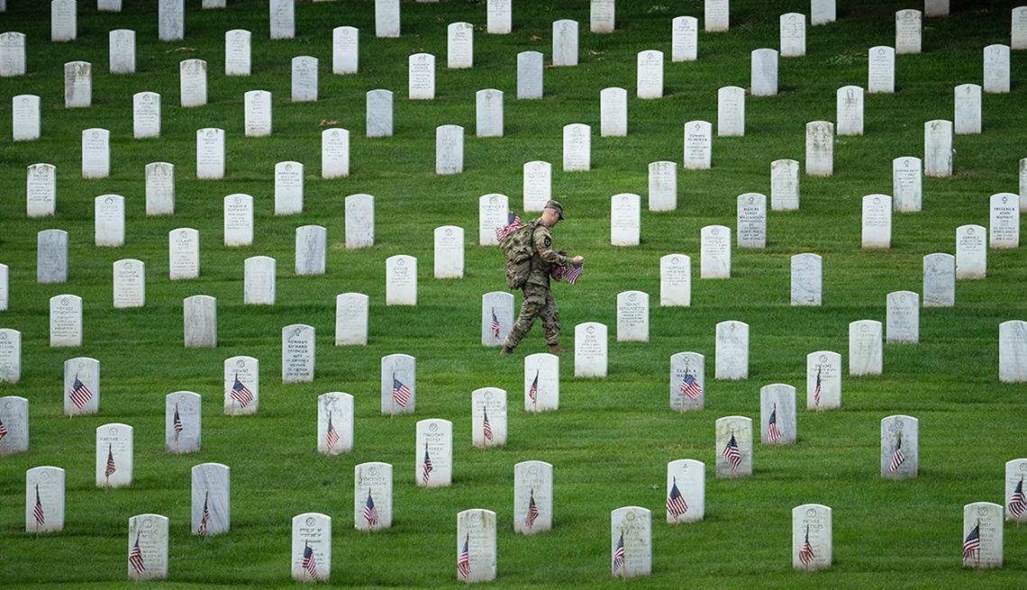 Más de 130 ceremonias del Día de la Recordación en cementerios del VA Un miembro del 3.er Regimiento de Infantería de EE. UU. coloca banderas en las lápidas del personal militar enterrado en el Cementerio Nacional de Arlington.