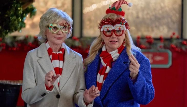 two women wearing matching red and white scarfs and christmas novelty eye glasses