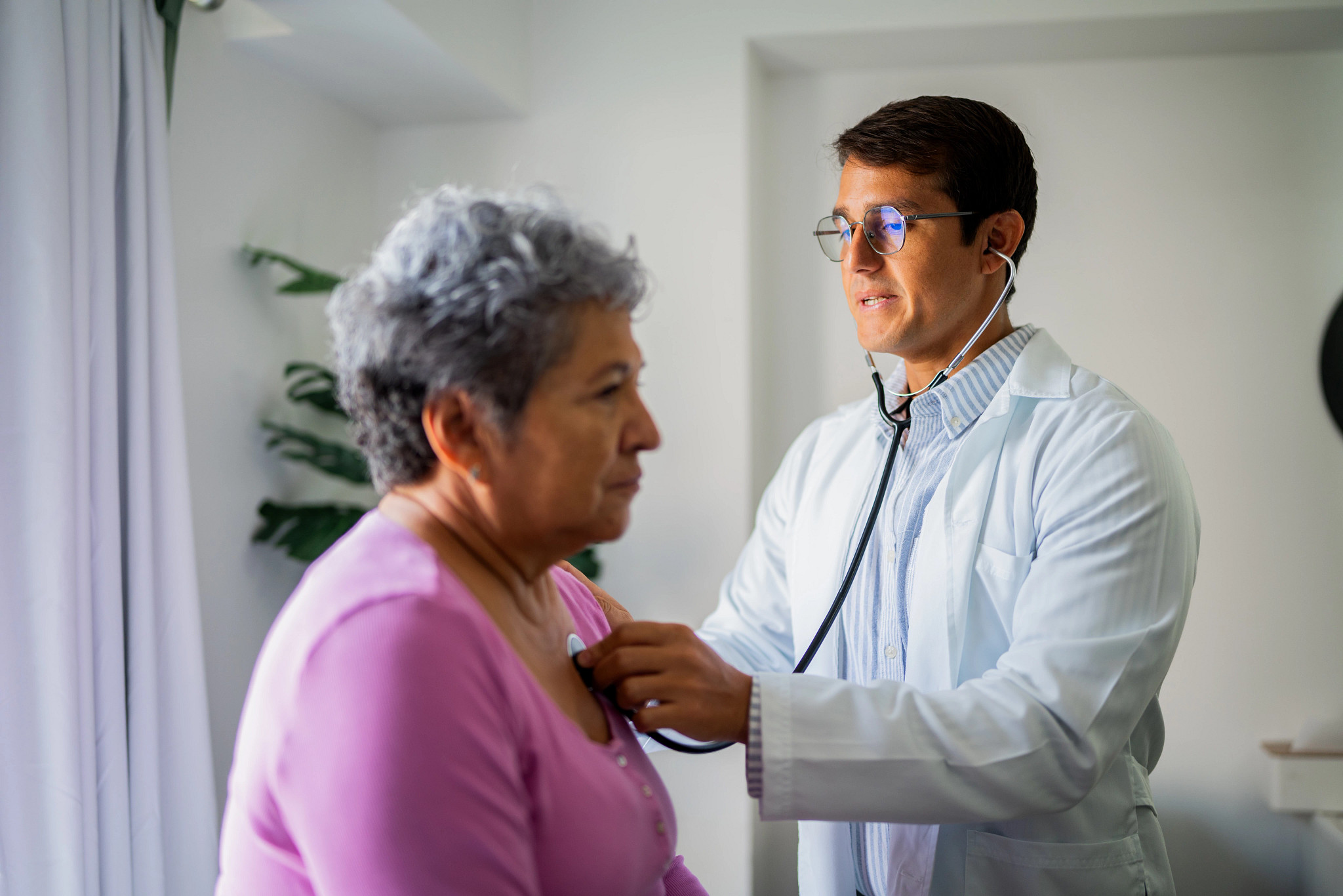 Doctor examining an older woman’s heart with a stethoscope during a medical visit.