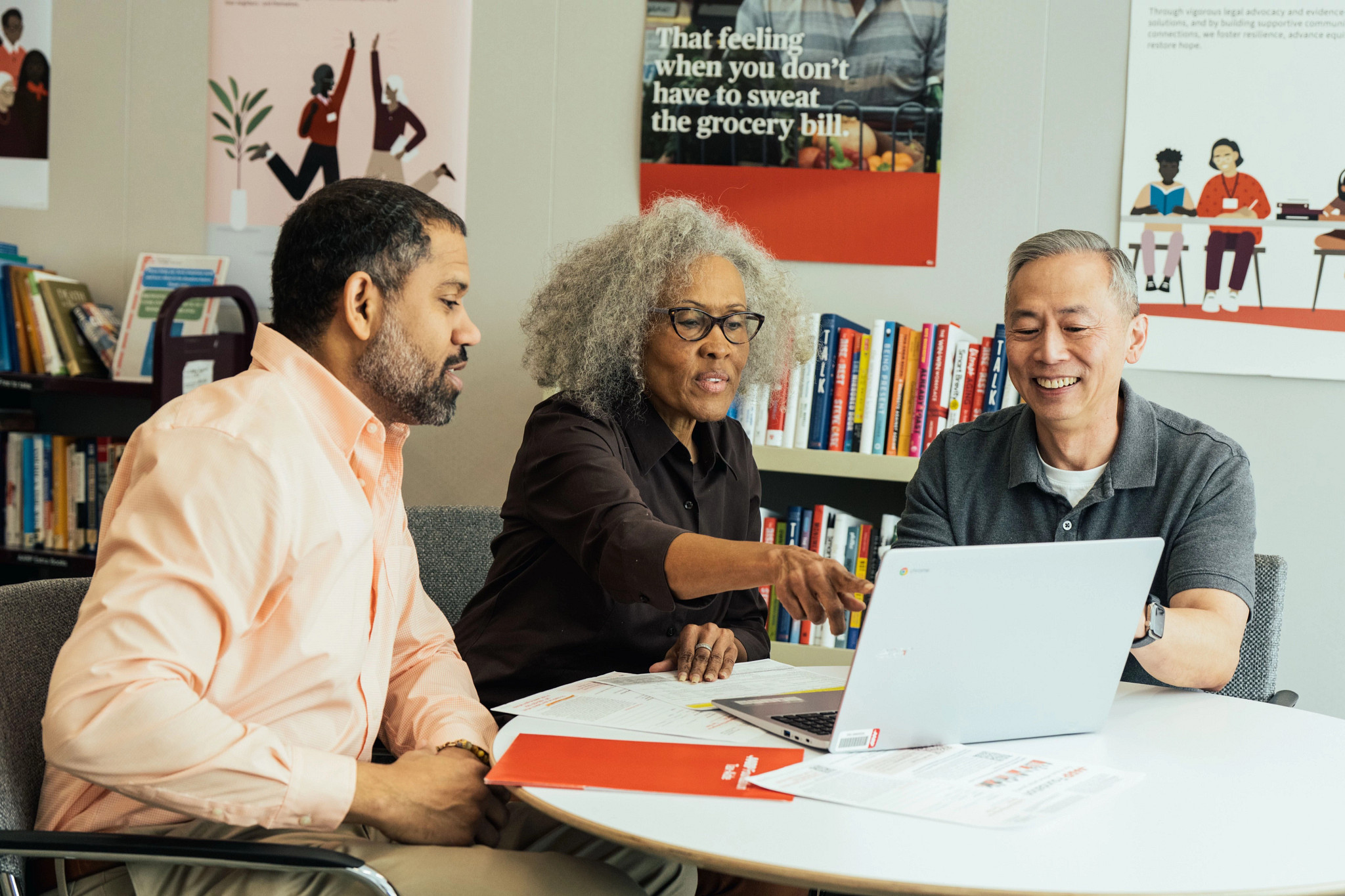 Three people in a library looking at a laptop computer