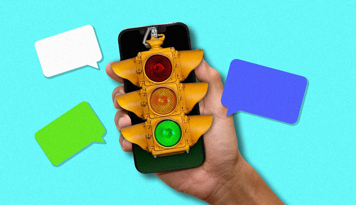 a stoplight with a person holding up a smartphone behind it