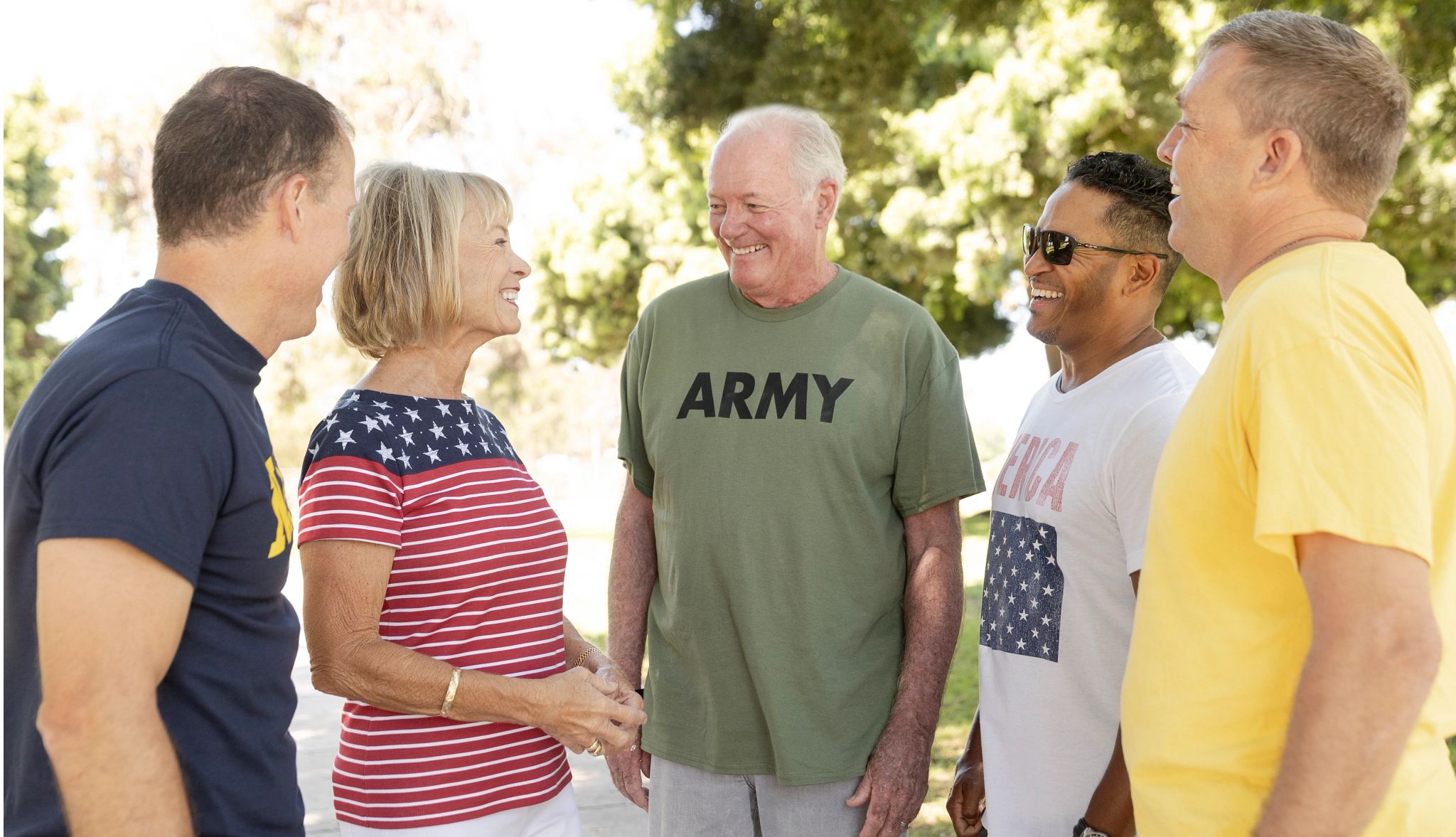 A diverse group of friends of all ages sport patriotic garb as they meet for a walk in a park on a sunny day A diverse group of friends of all ages sport patriotic garb as they meet for a walk in a park on a sunny day