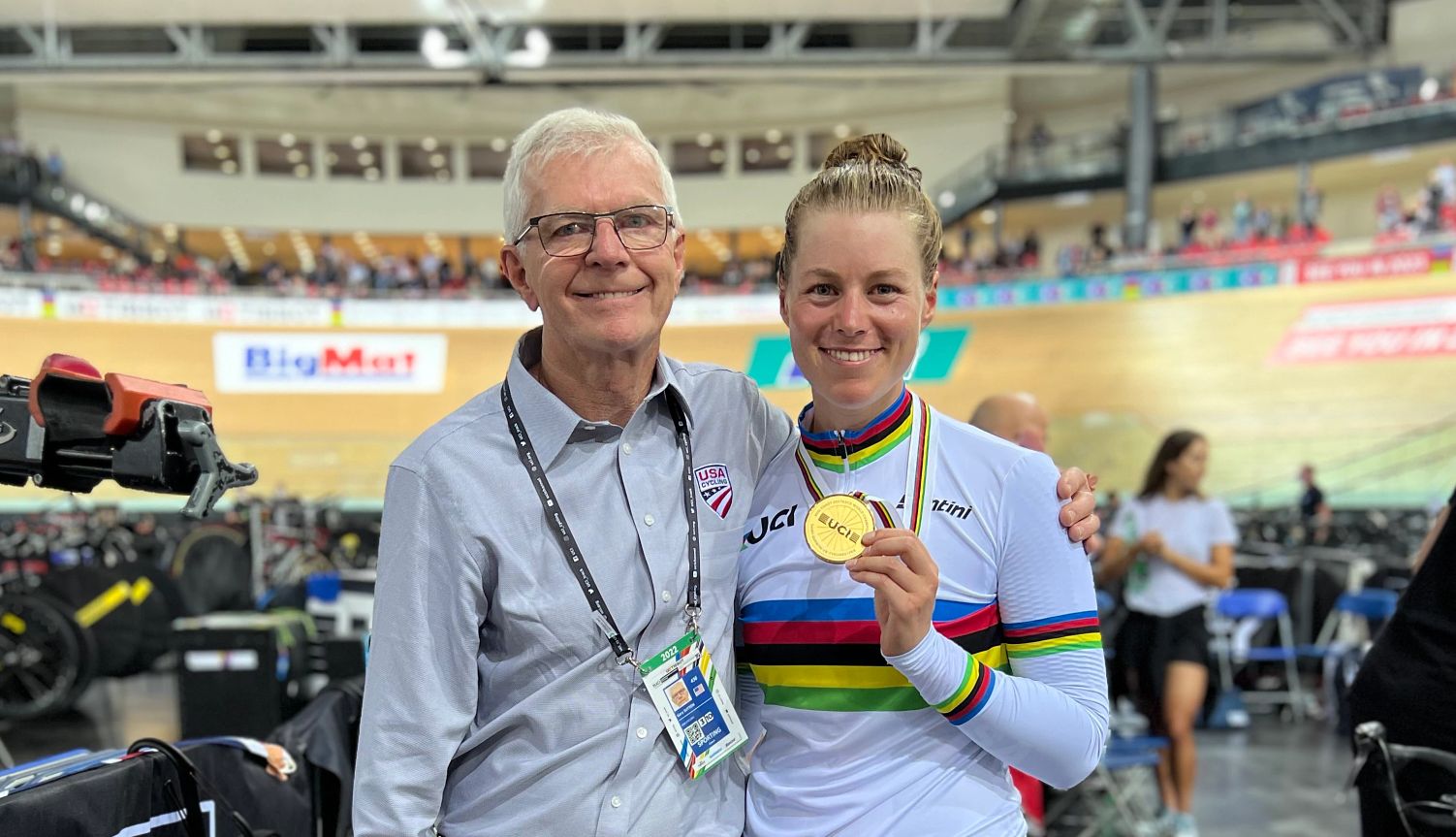 Coach Gary Sutton and professional cyclist Jennifer Valente Coach Gary Sutton and professional cyclist Jennifer Valente holding a medal in a stadium