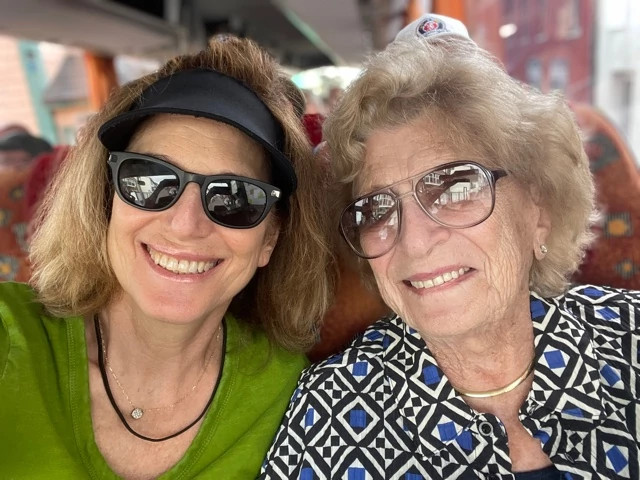 Two people smiling together outdoors, sharing a joyful cross-generational moment