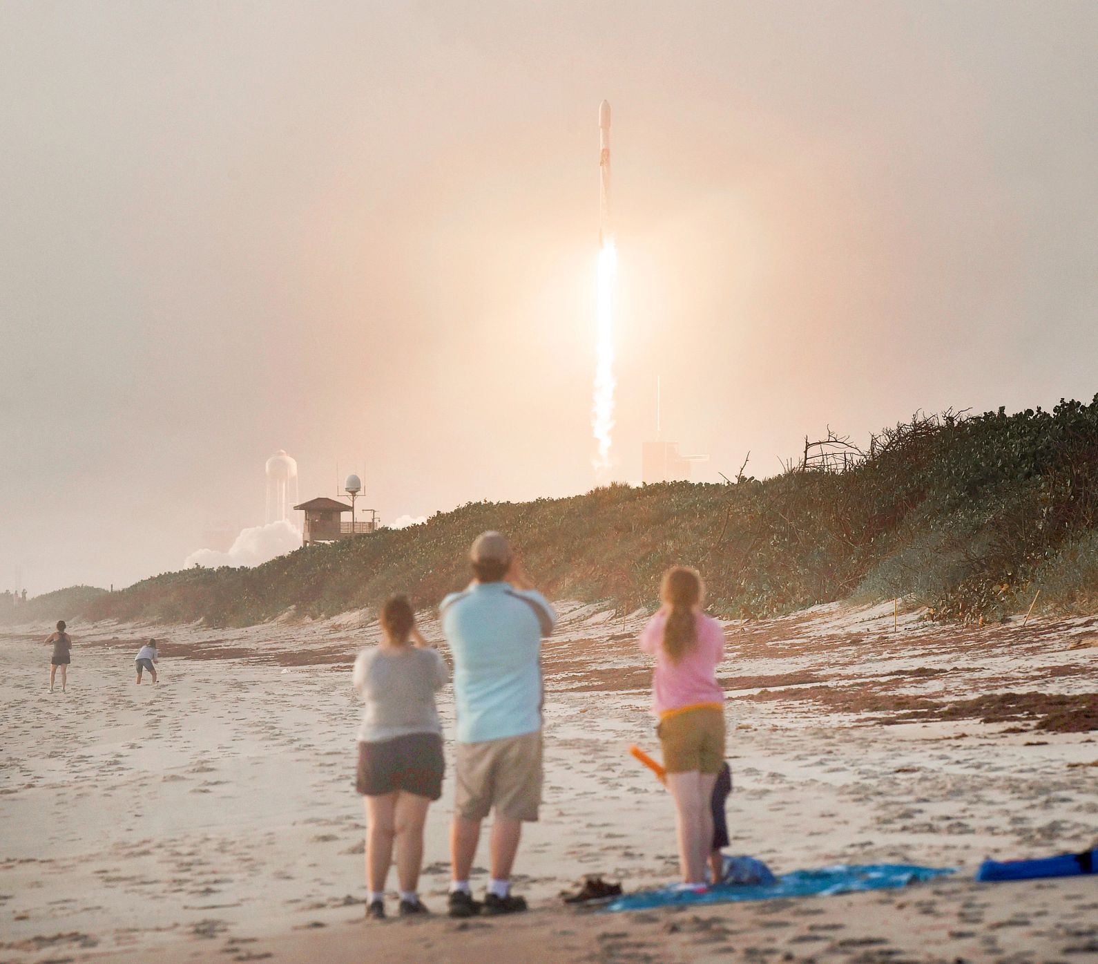 Bucket List Beach Experiences a rocket launches in the distance as spectators watch in the foreground on a beach