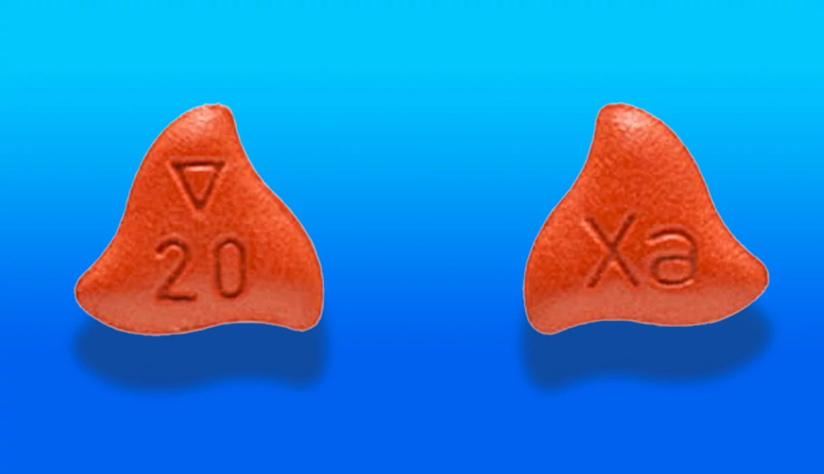 two Xarelto pills on a blue background, the pills are shaped like a flame