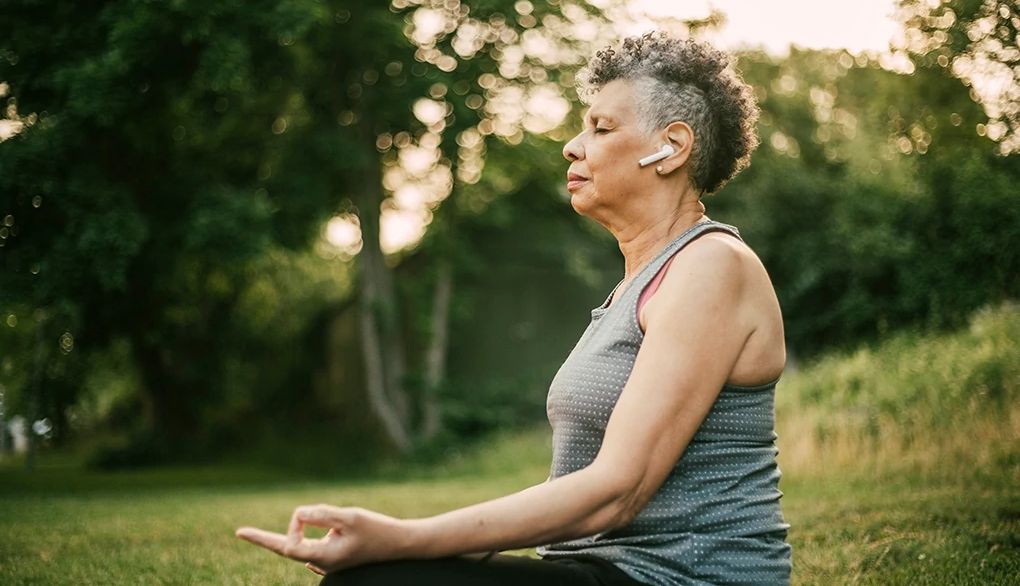 Mindfulness is about paying attention to our present moment Side view of woman sitting outside in a lotus position