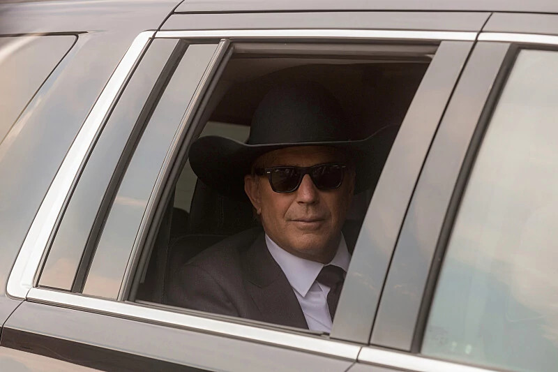 Kevin costner in a car wearing a cowboy hat