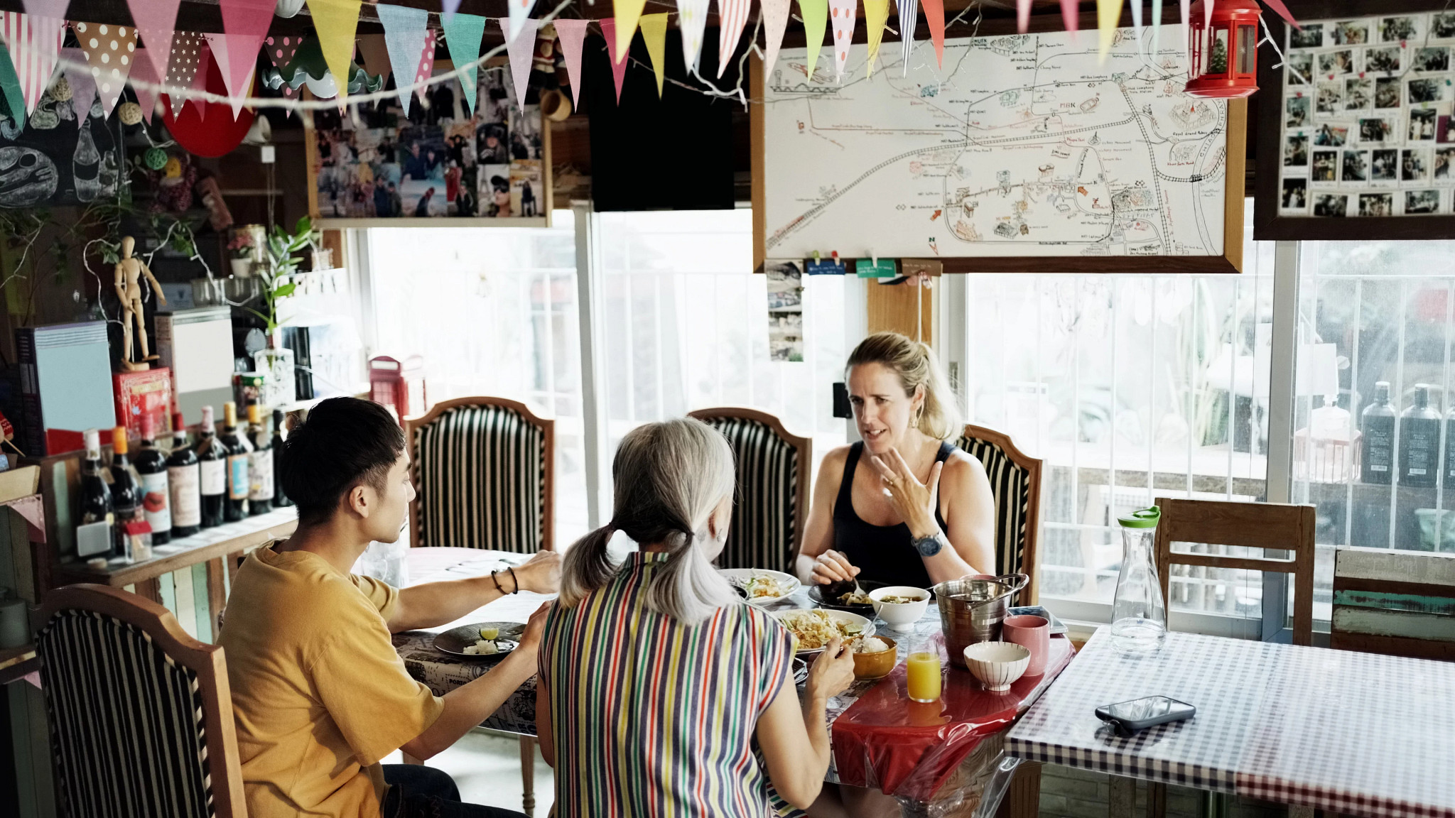 a woman talking with her teacher over plates of food at a table during a cooking class