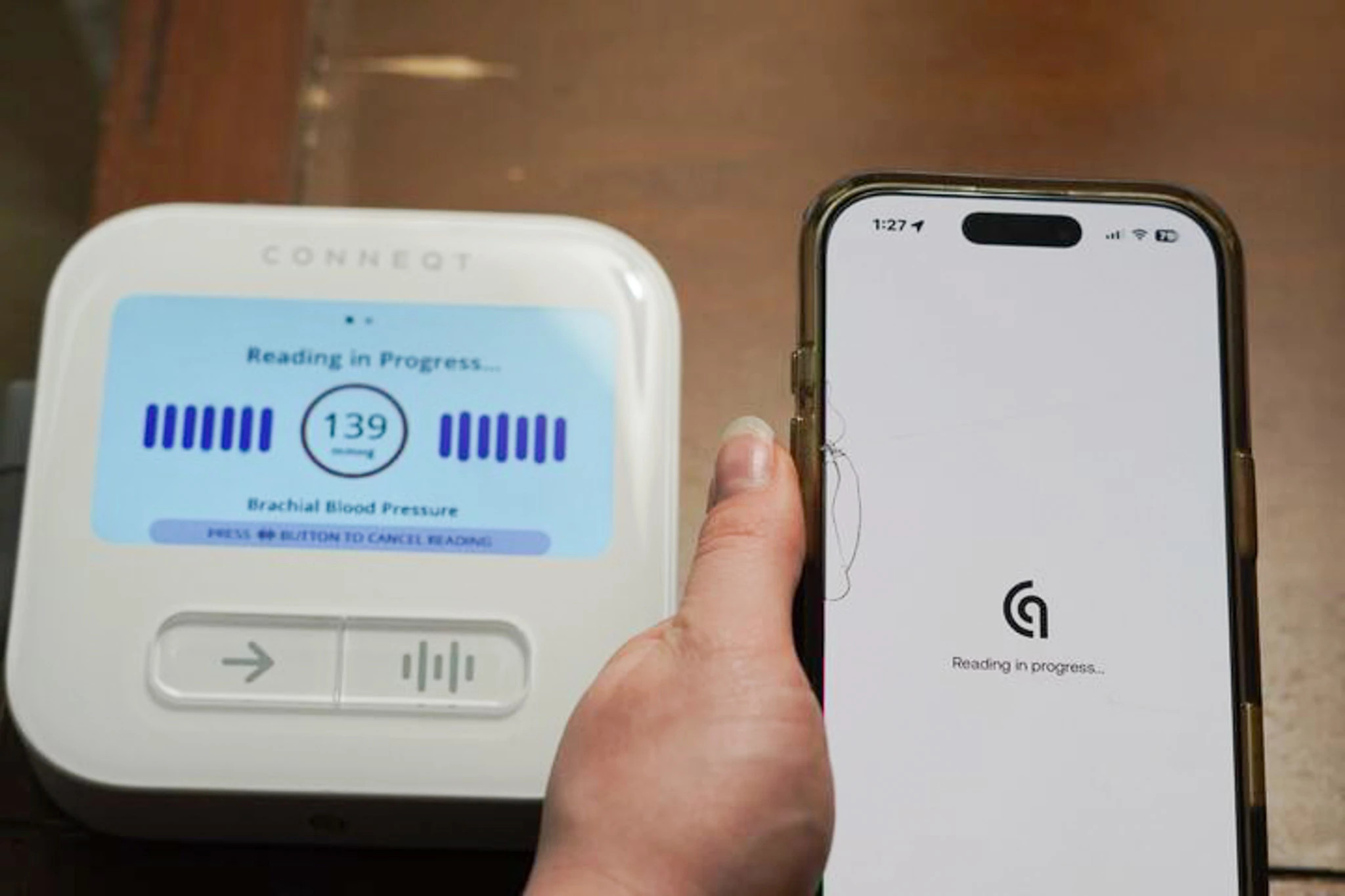 Someone holding their phone next to the CONNEQT Pulse blood pressure monitor.