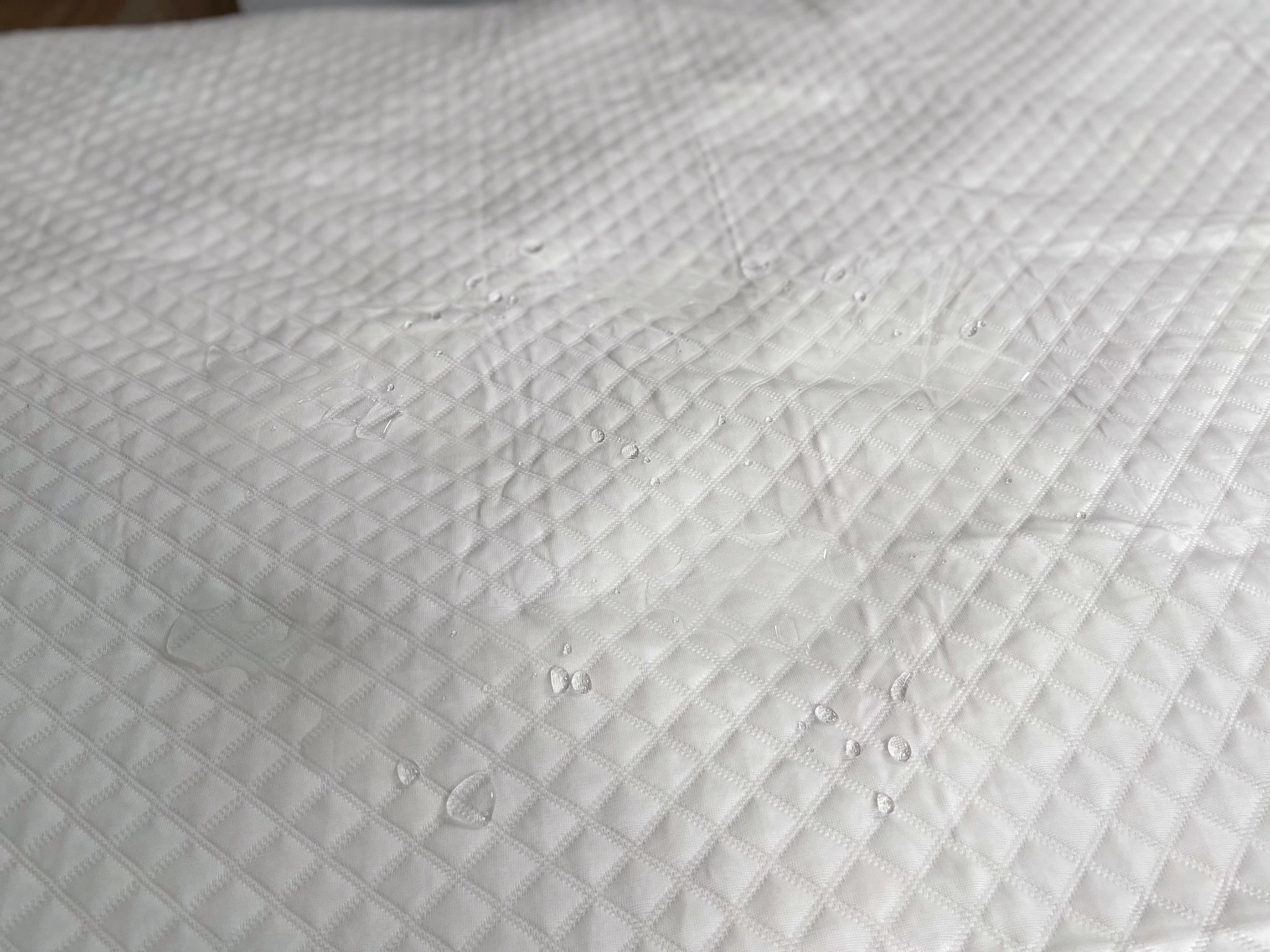 Water droplets pooling on top of the Silk & Snow Mattress Protector