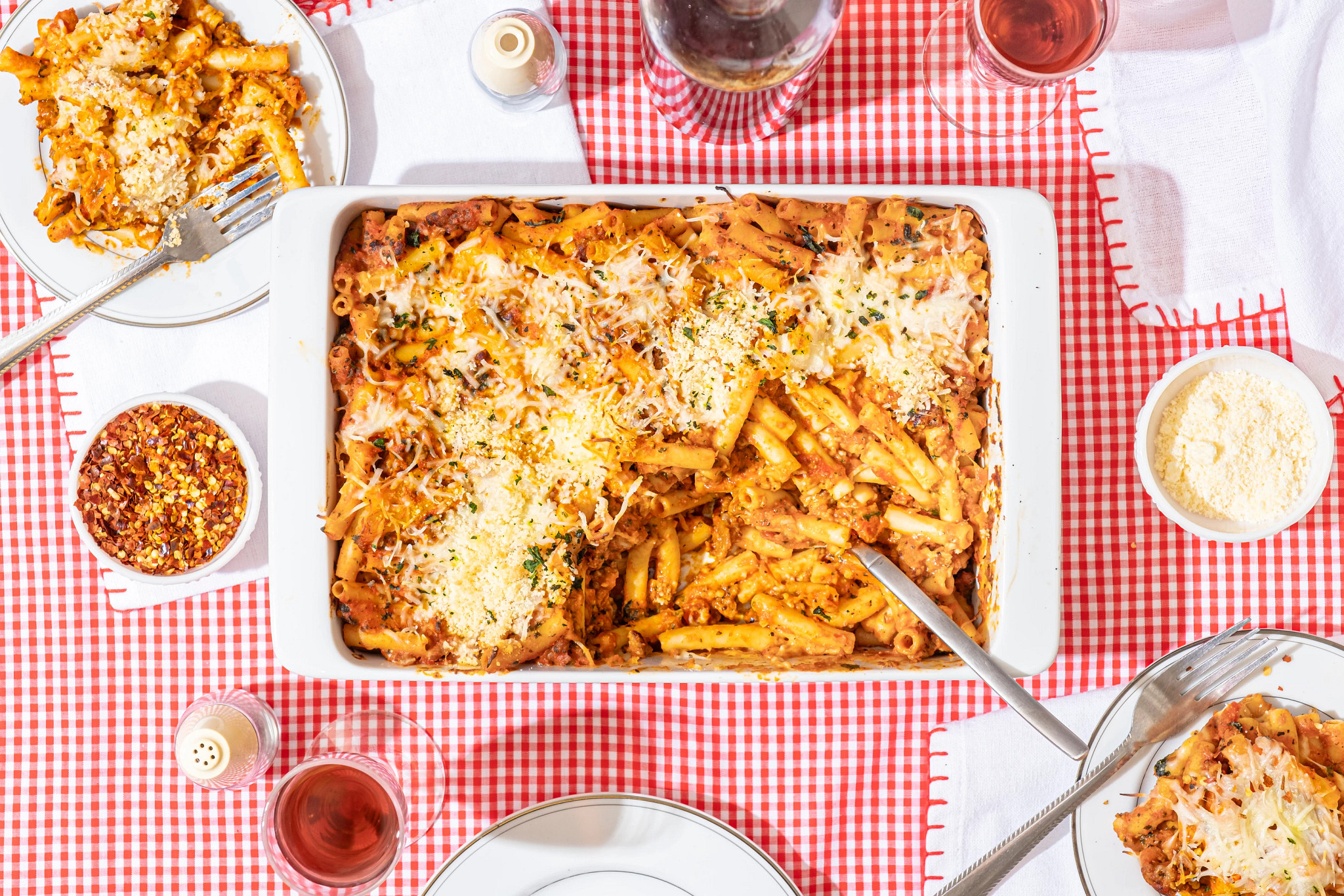 Pan of ziti casserole from overhead with white and red checkered table cloth