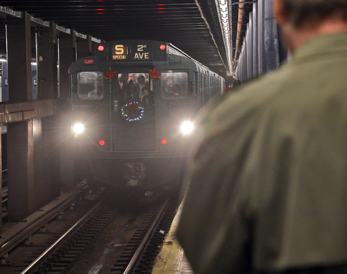 a packed subway train with a wreath on the front