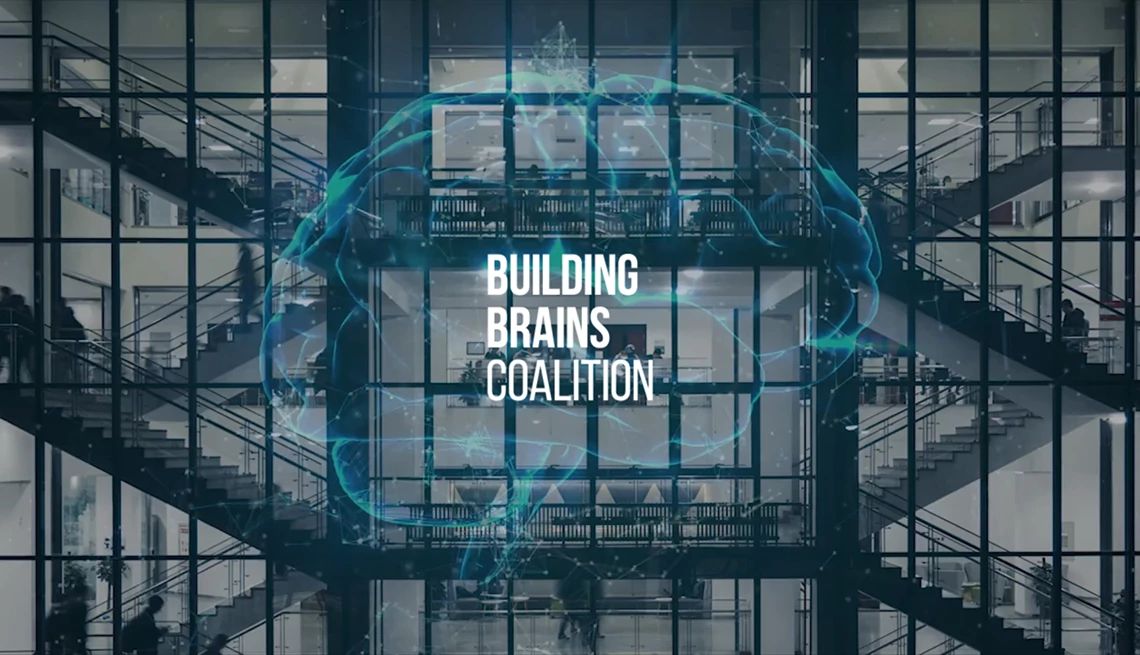 Building Brains Coalition helps create environments that foster resilience and cognitive thriving Staircases in an office building with the outline of a brain and the text "Building Brain Coalitions" overlaying it