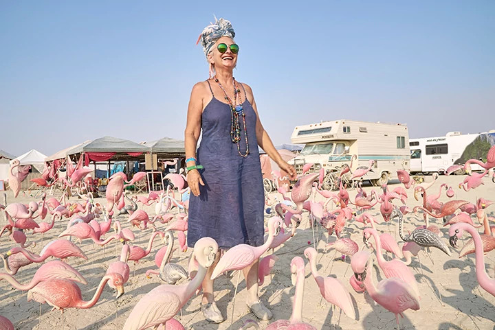 a woman standing among a flock of flamingos