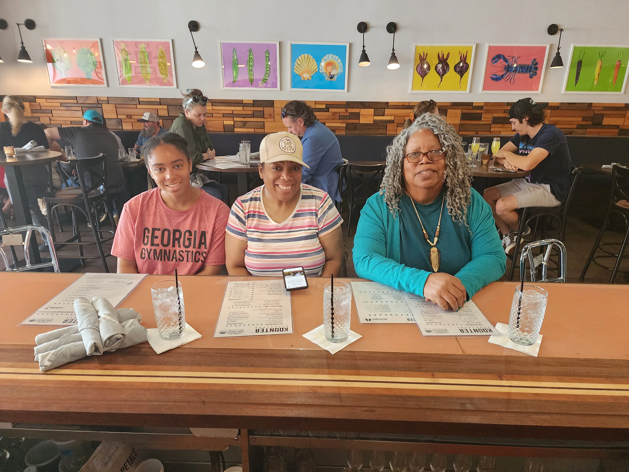 three women smiling while sitting at a table in a restaurant