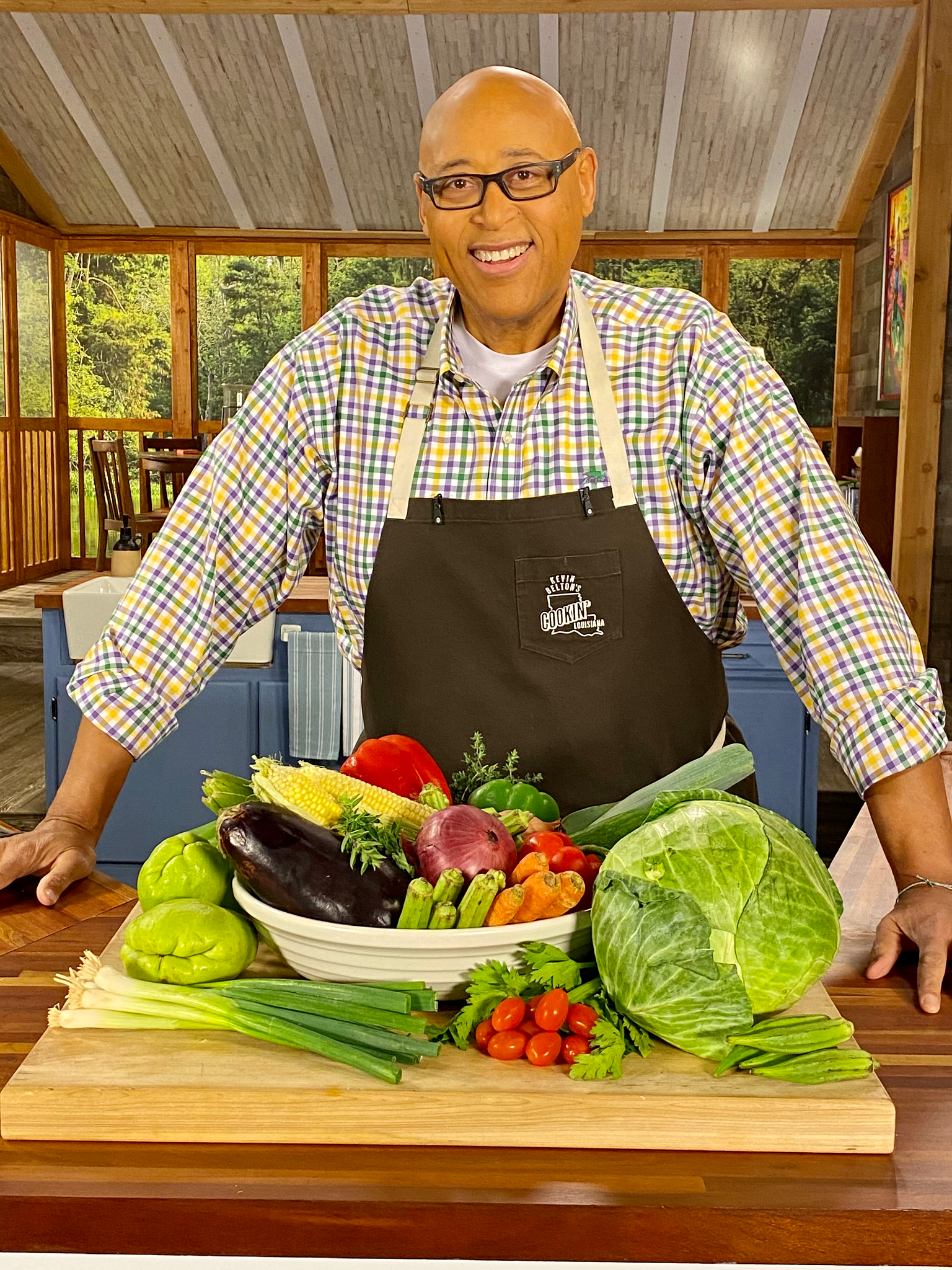 Chef Kevin Belton standing in front of a wooden board full of vegetables