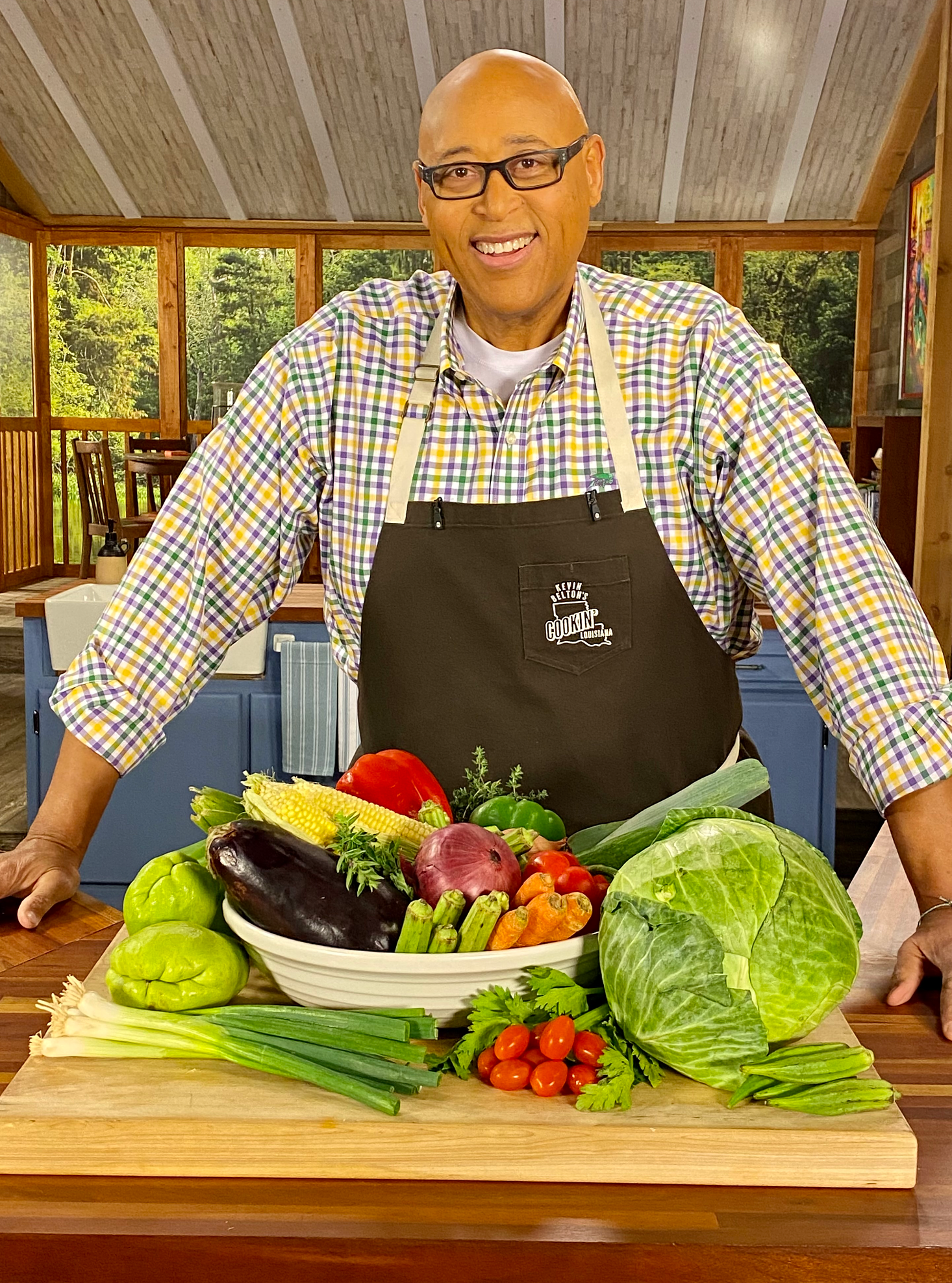Chef Kevin Belton standing in front of a wooden board full of vegetables