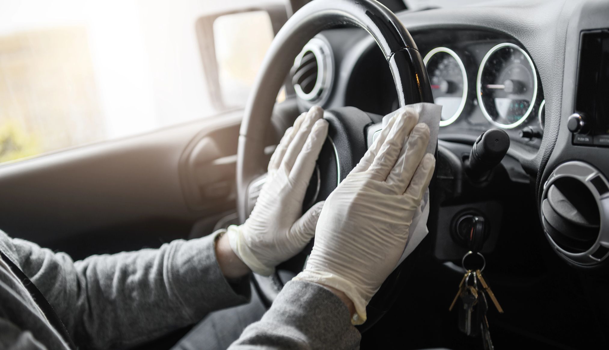 Cleaning the interior of vehicle Person wearing gloves wiping down steering wheel inside vehicle