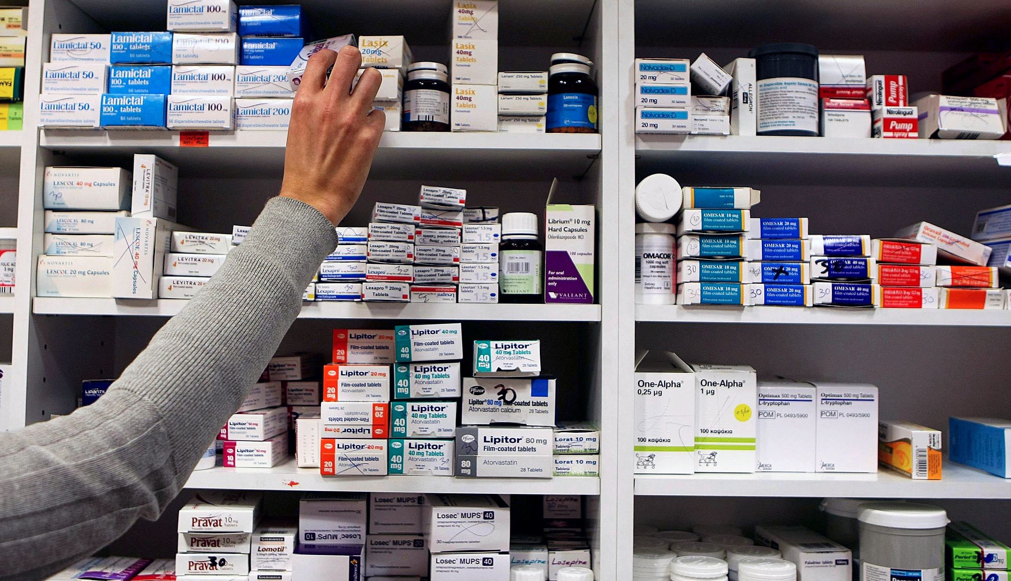 Un farmacéutico alcanzando una caja de medicamentos recetados