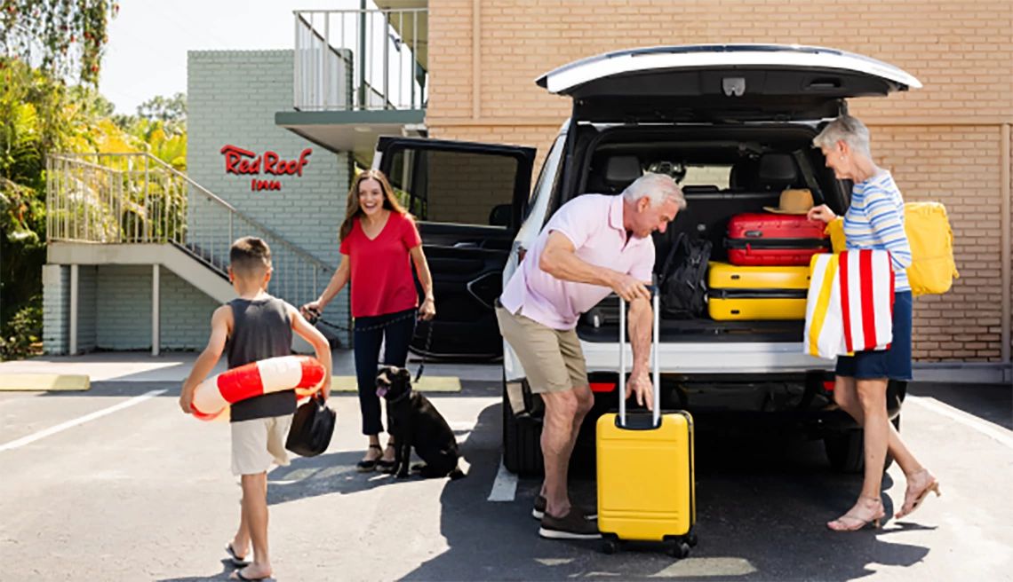 Family taking their luggage out of the car in front of a hotel