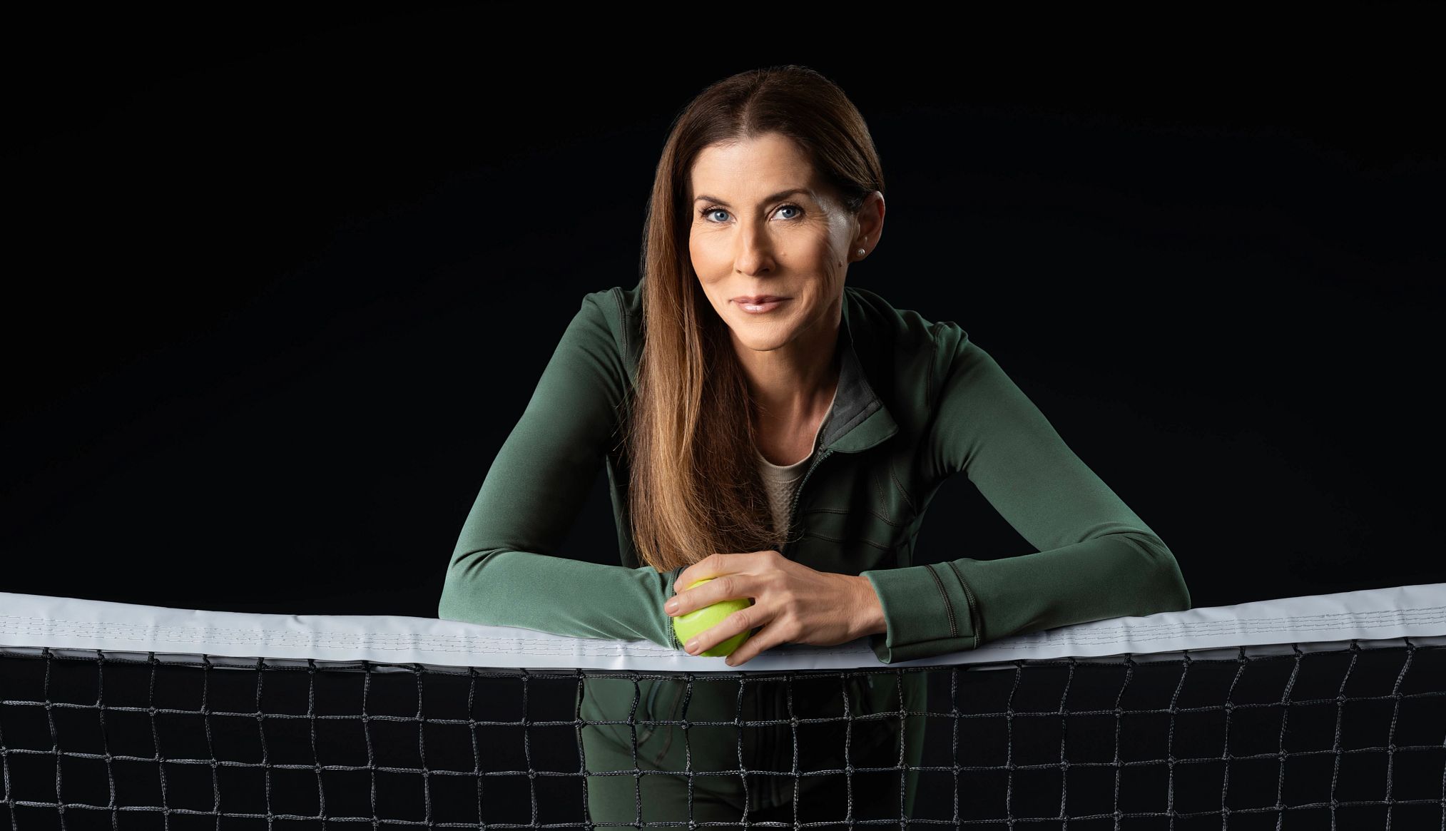 Monica Seles on Living With Autoimmune Disease monica seles smiling while leaning on a tennis netv